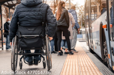 Rollstuhlfahrer und Fahrgäste warten auf Bus