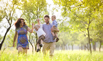 Eine junge Familie genießt die Natur. Mutter und Vater sind bei einem Spaziergang mit ihren beiden kleinen Kindern.