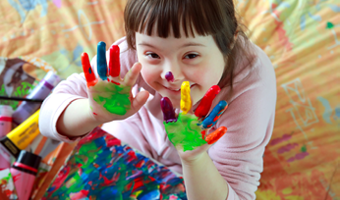 Ein Mädehen mit autistischer Behinderung  beim Spielen mit Farben