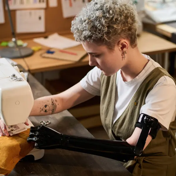 Frau mit Armprothese arbeitet an einer Nähmaschine